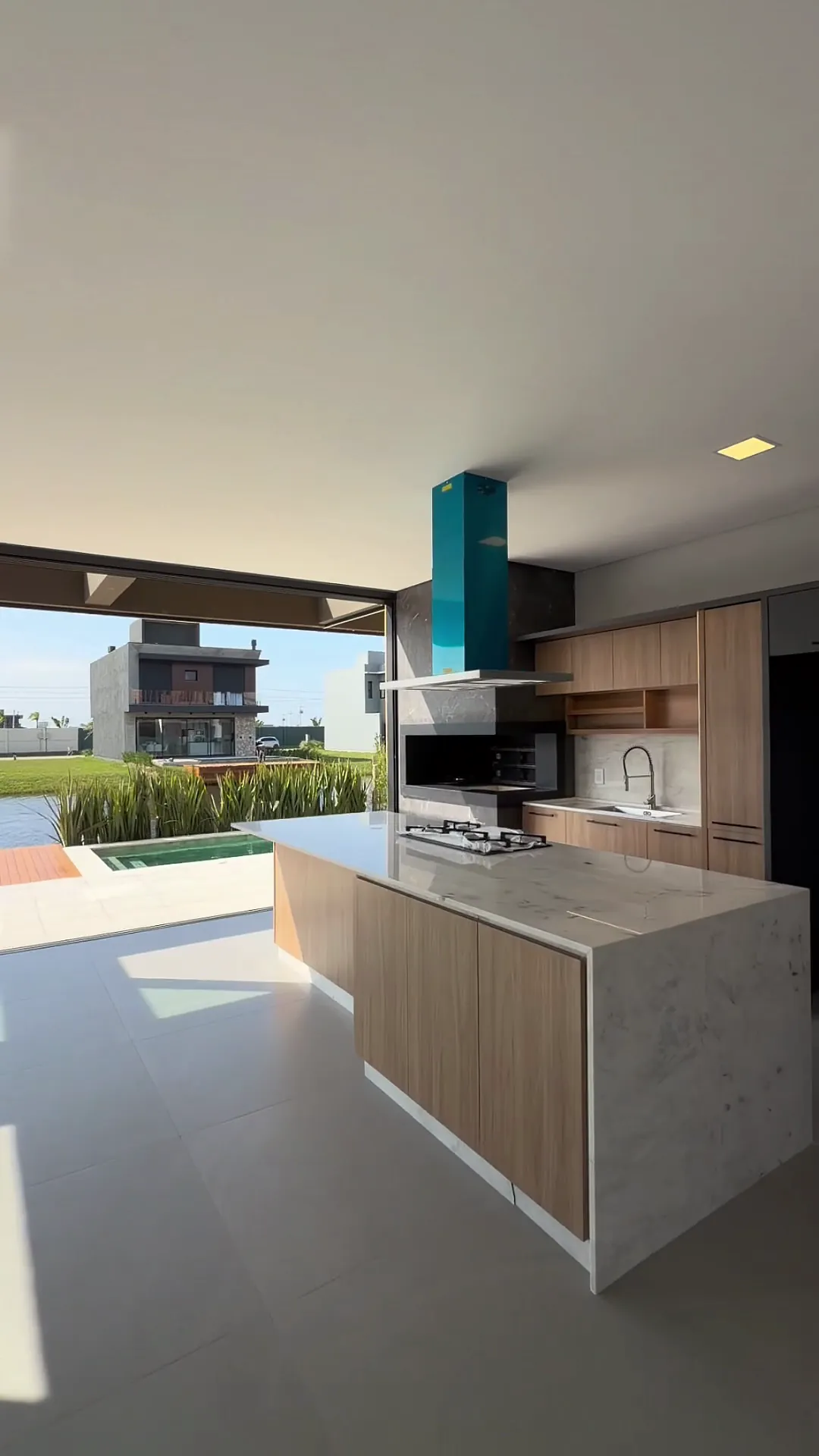 Área gourmet integrada com ilha e vista para a piscina